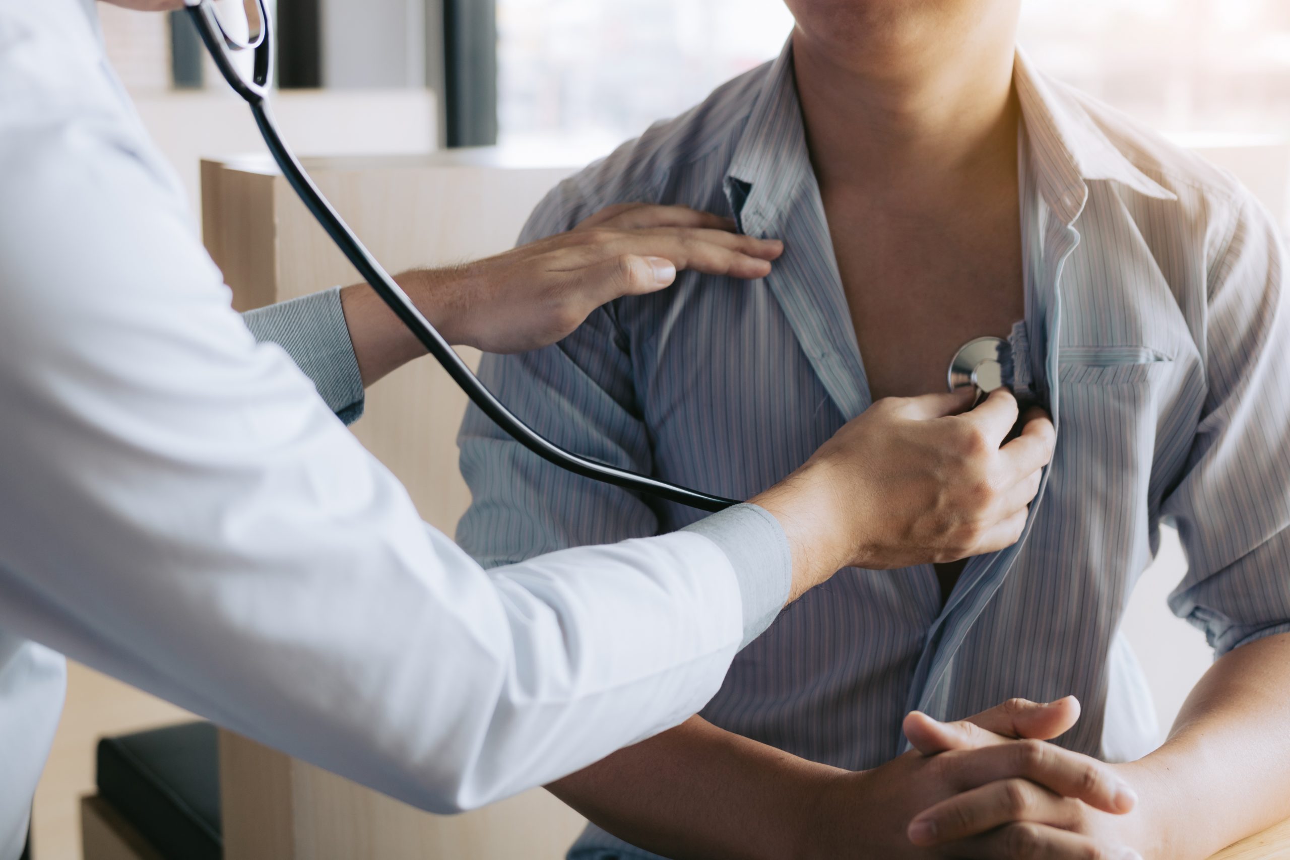 Doctor uses stethoscope to monitor heart of patient.