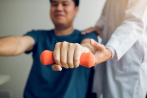 Physiotherapist helping a patient to use light weights
