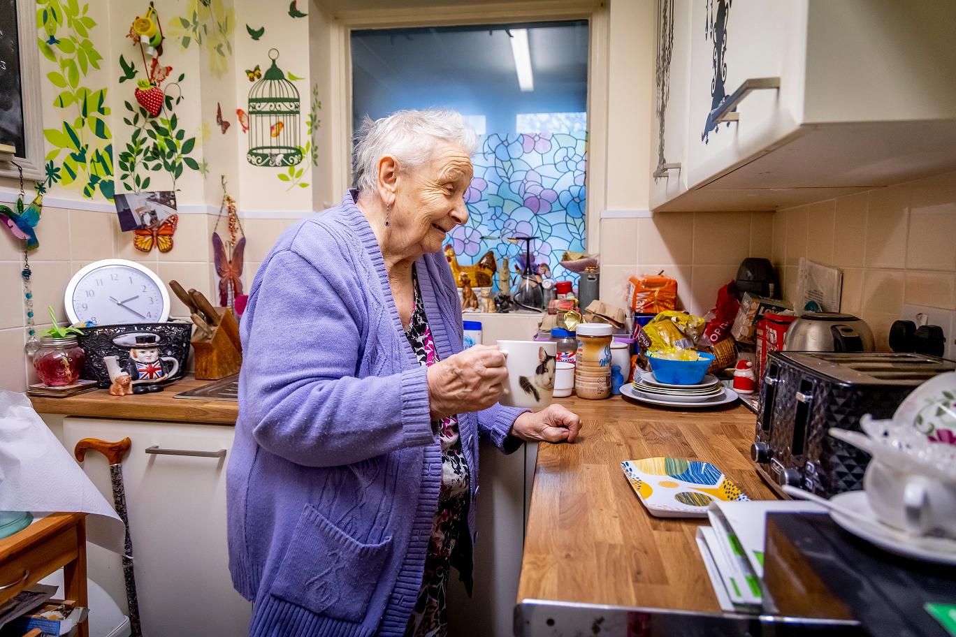 Older lady standing in her kitchen making a cup of tea