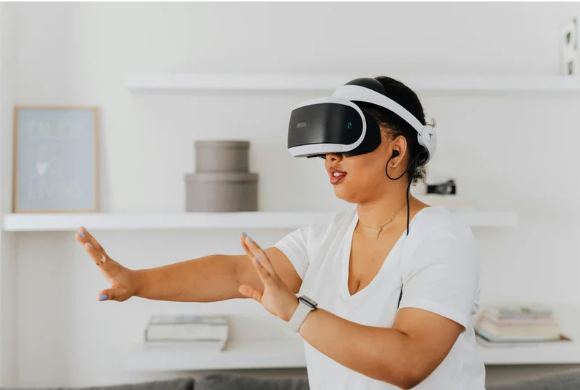A woman is wearing an augmented reality headset, earphones, and a smart watch. She is taking part in physical rehabilitation using these technologies.